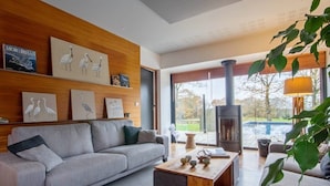 A modern living room with a grey sofa, wooden coffee table, and wall art.