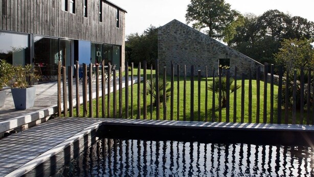 A modern building with a wooden facade and a stone structure in the background.
