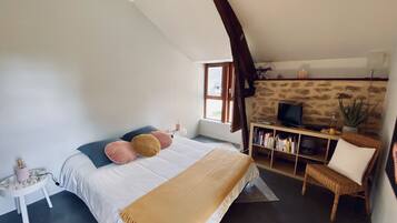 Um quarto com uma cama, uma televisão, uma estante e uma janela.