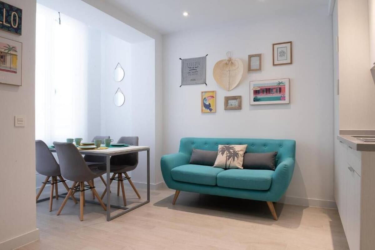 Un espace de vie moderne avec un canapé de couleur turquoise, une table à manger avec des chaises et des œuvres d’art murales.