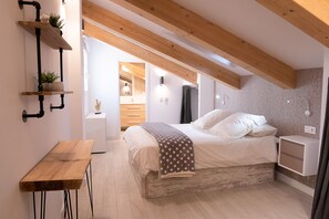 A bedroom with a wooden ceiling, a bed with white bedding, a nightstand, and a small table with a plant. - Besalamanca (Salamanca)