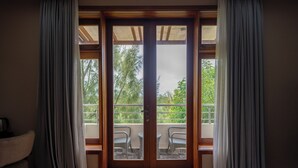 A room with a sliding glass door leading to an outdoor balcony with two chairs and a table. - Maiyan Luxury Resort (Nanyuki)