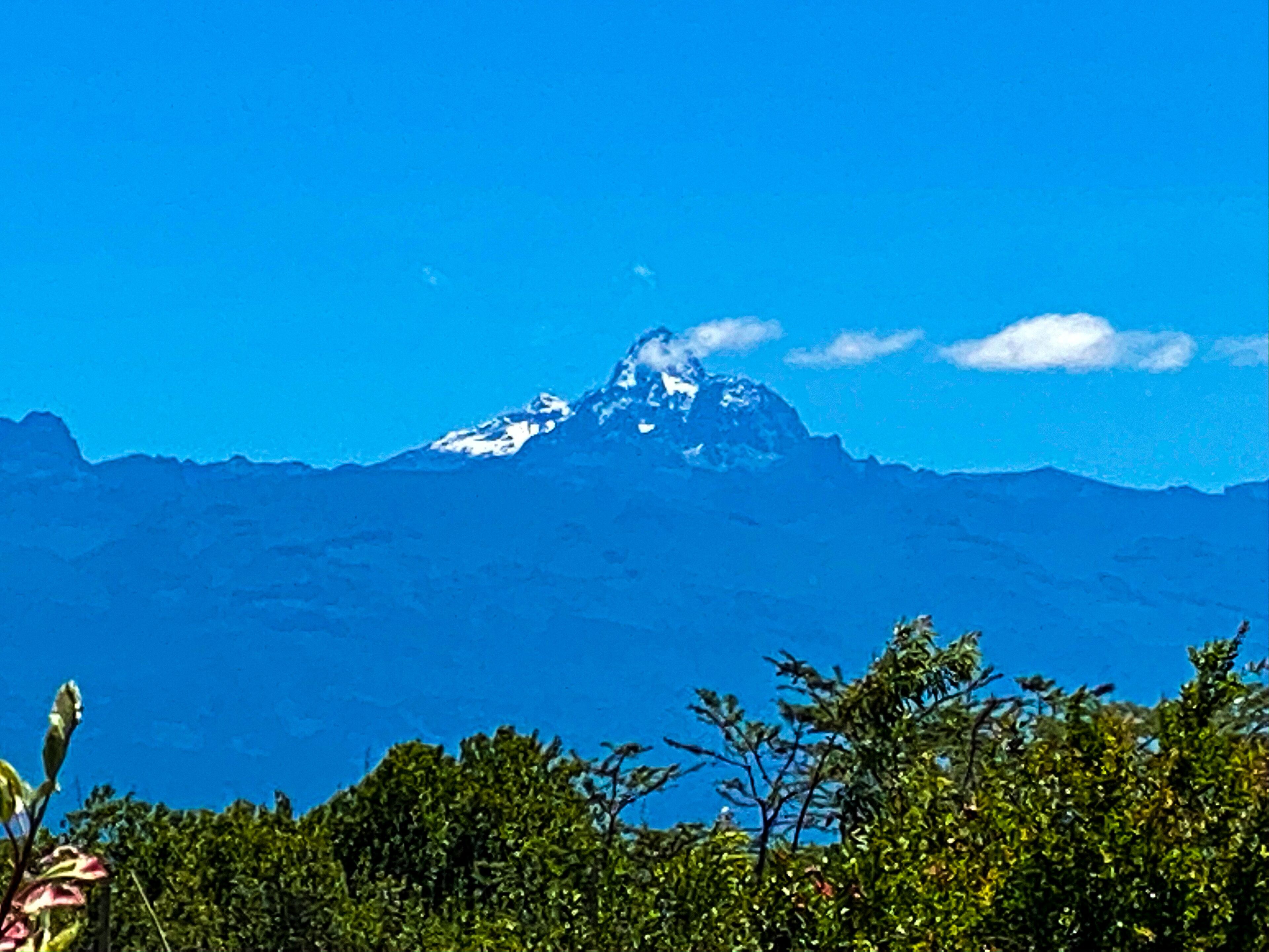 A mountain with a snow-capped peak under a clear blue sky.