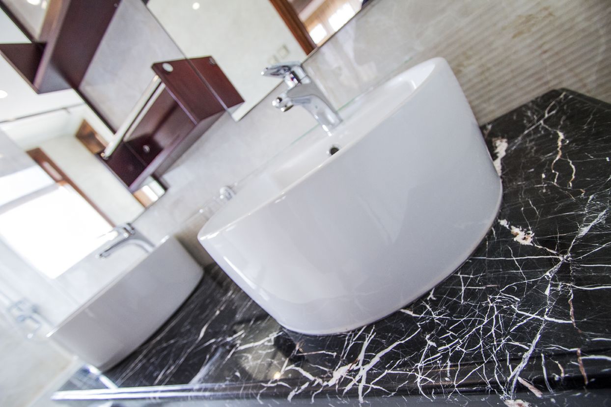 A bathroom with a white sink and a marble countertop.