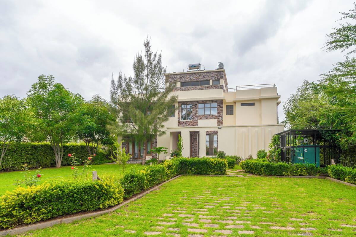 Una casa moderna de dos pisos con un jardín cuidado y un depósito de agua en el techo.