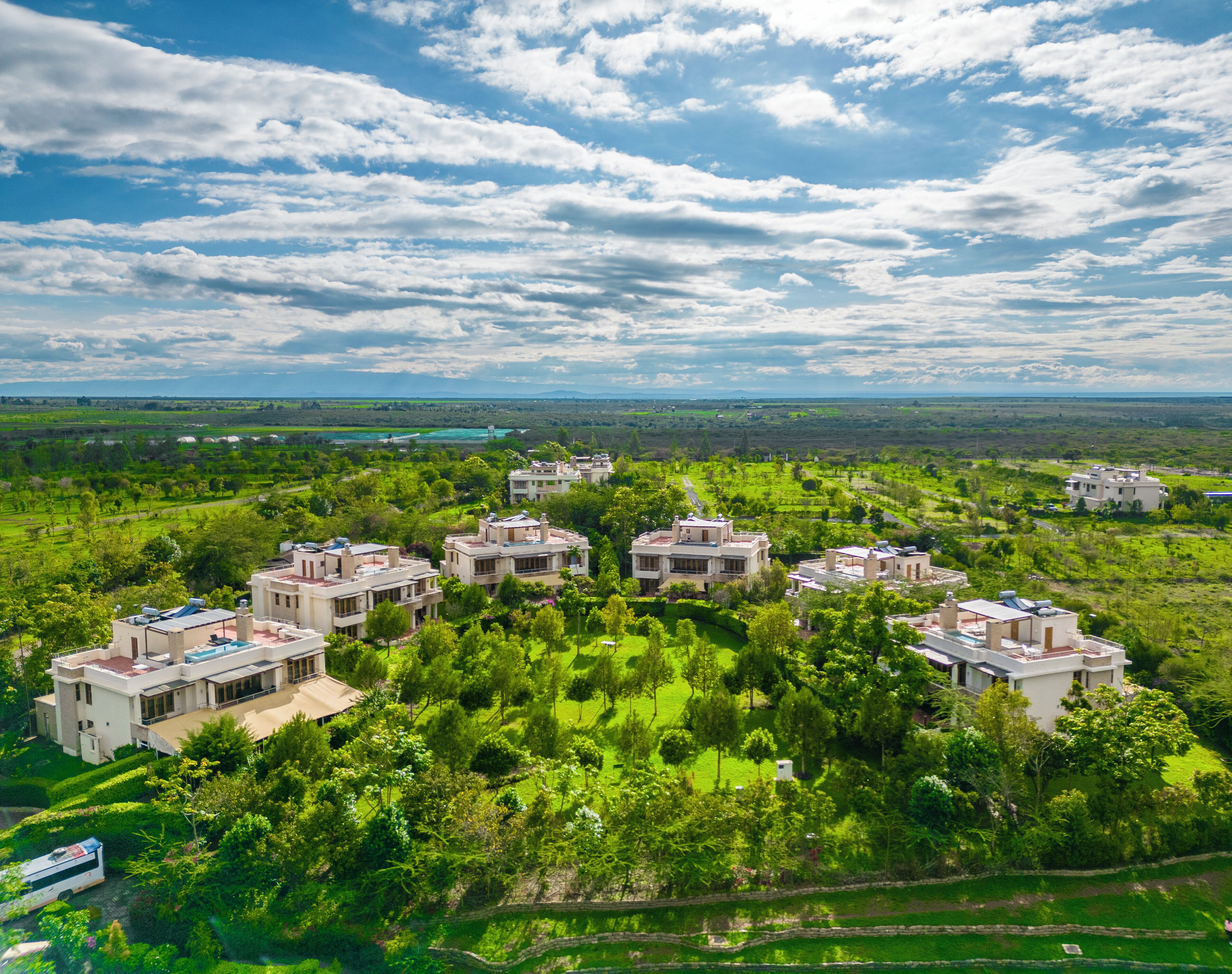 A residential area with multiple houses surrounded by lush greenery and a clear sky.