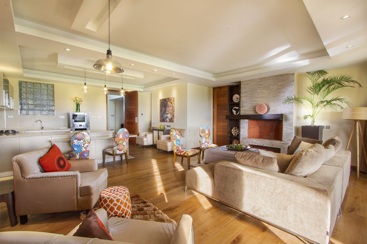 A spacious living room with a fireplace, modern furniture, and a kitchen in the background.