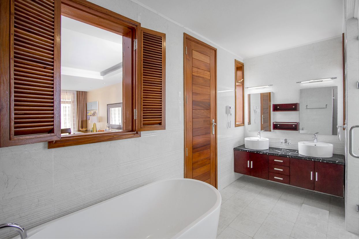 A modern bathroom with a freestanding bathtub, two sinks, and wooden doors.