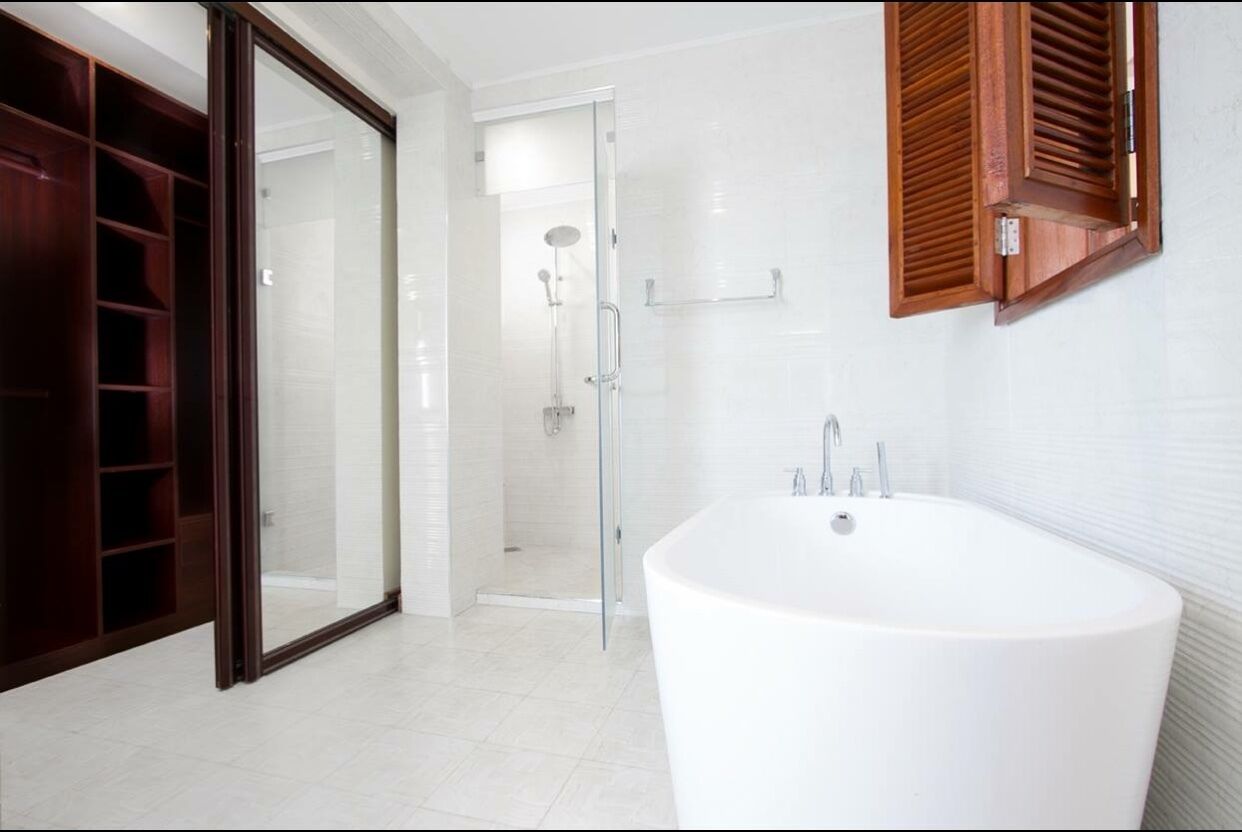 Un baño moderno con una bañera independiente, ducha con mampara de vidrio y un mueble de madera.