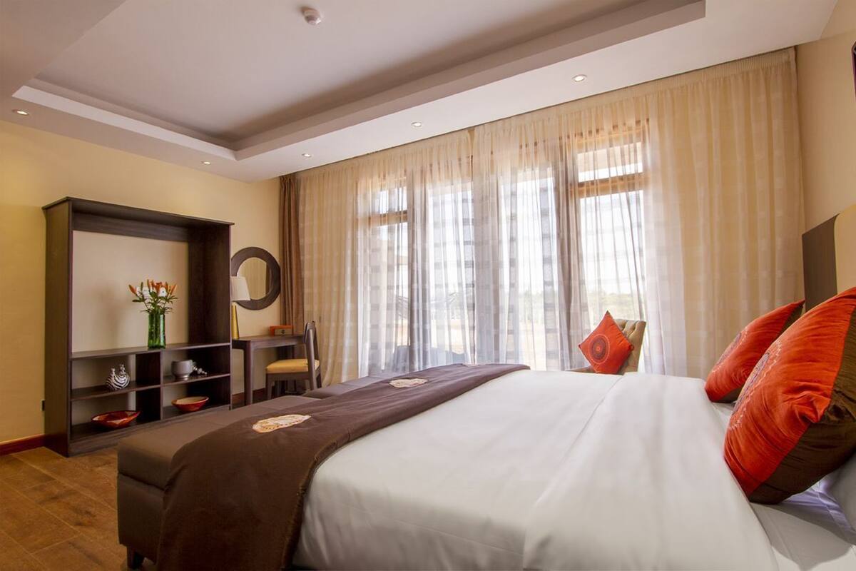 Una habitación de hotel con una cama grande, un escritorio, una silla y una estantería.
