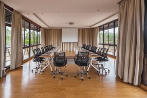 A conference room with a long table, chairs, and a projector screen.