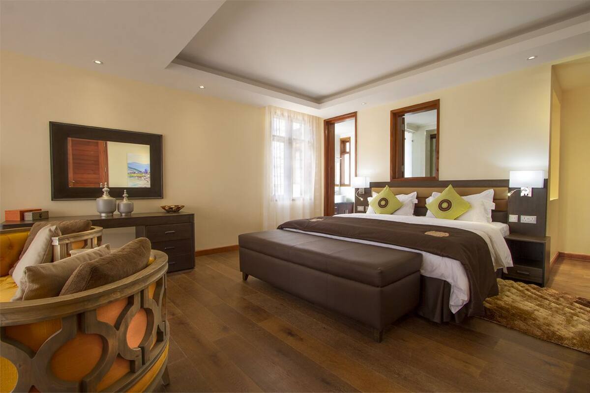 Una habitación de hotel con cama, escritorio, silla y un espejo grande.