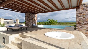 A rooftop pool area with a hot tub, lounge chairs, and a stone wall. - Maiyan Luxury Resort (Nanyuki)