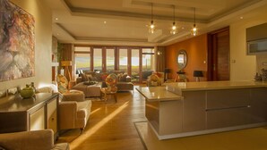 A spacious living room with a large window, a central island, and a dining area. - Maiyan Luxury Resort (Nanyuki)