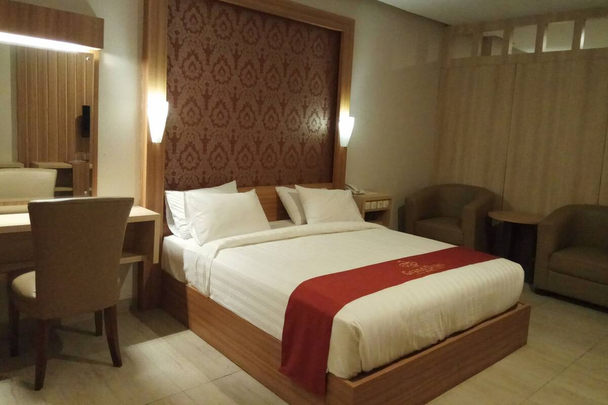 Una habitación de hotel con una cama grande, un escritorio y dos sillas.