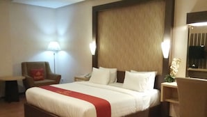 Une chambre d’hôtel avec un grand lit, un bureau, une chaise, une lampe et une table de chevet.