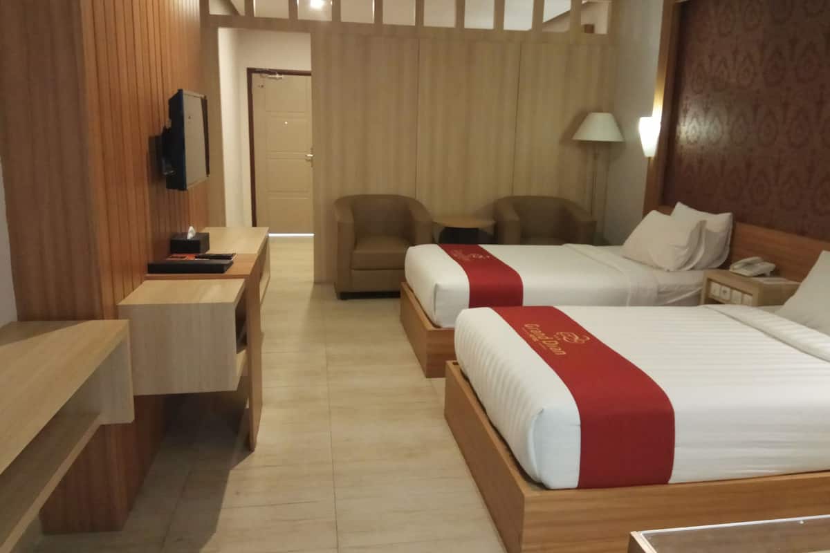 Habitación de hotel con dos camas, un escritorio, una silla y un televisor.
