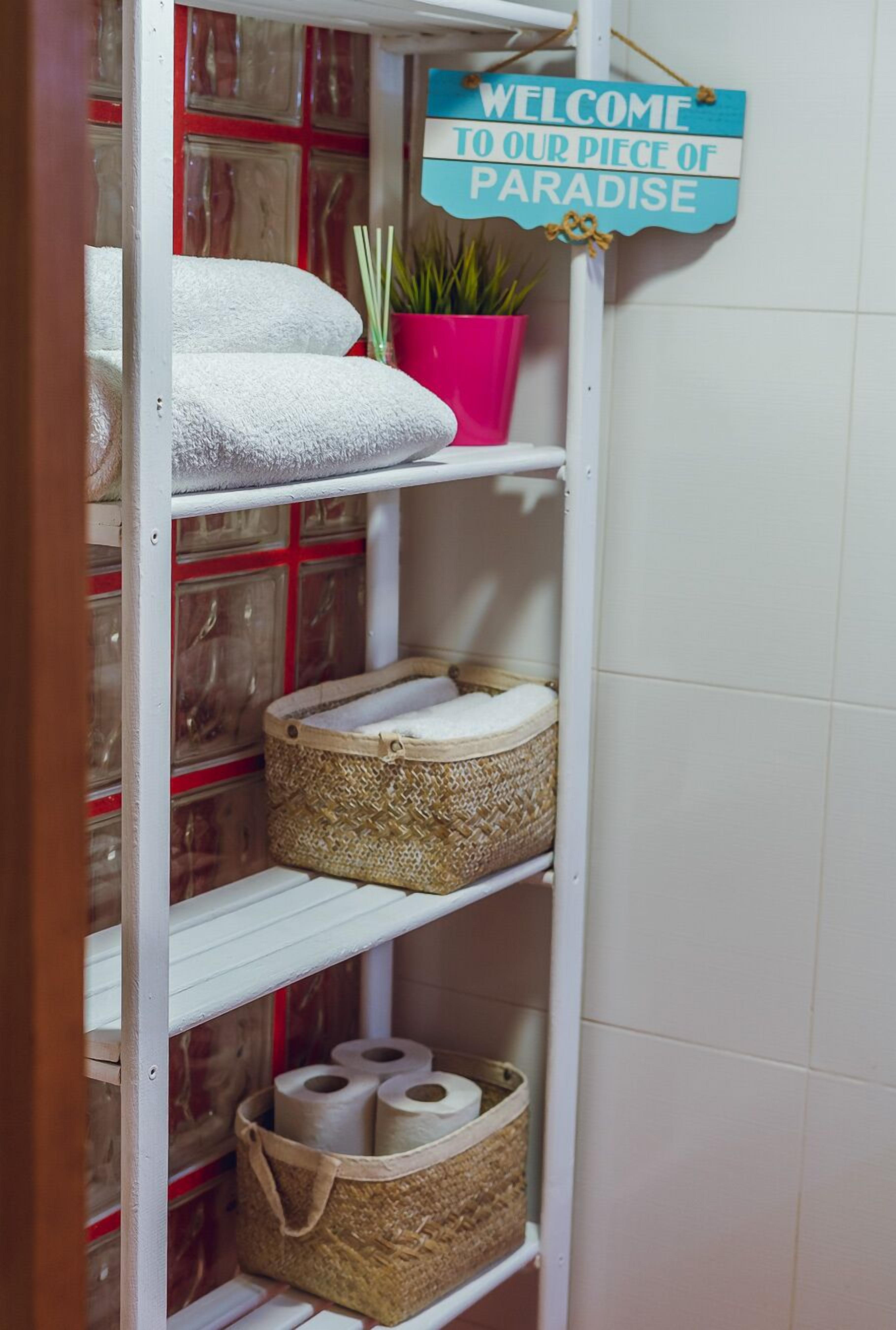 A shelf with towels, a potted plant, and a welcome sign.