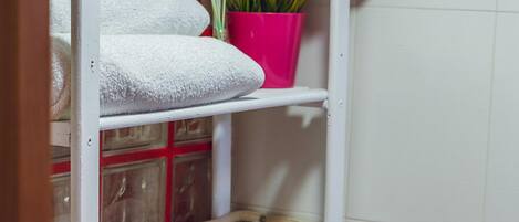 A shelf with towels, a potted plant, and a welcome sign.