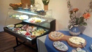 A buffet with various dishes and a decorative vase with flowers. - Landgasthaus Fecht (Aurich)