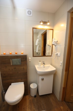 A bathroom with a wooden vanity, a white sink, a mirror, and a toilet. There are candles on the vanity and a hairdryer on the wall. - Maryna House - Apartament Tradycyjny (Zakopane)