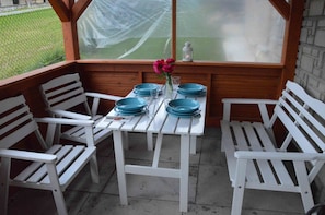 A table set with blue plates, white chairs, and a vase with pink flowers. - Maryna House - Apartament Tradycyjny (Zakopane)