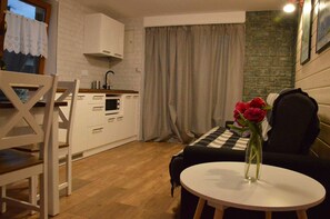 A compact living space with a kitchenette, a dining area, and a seating area with a table and a vase of flowers.