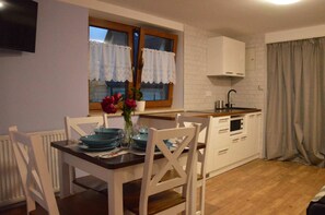 A compact kitchen with white cabinetry, a wooden countertop, and a dining table with chairs.