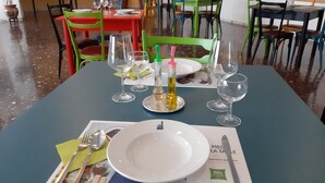 A dining area with tables set for two, featuring a variety of chairs and a menu on the table. - ibis styles Trani (Trani)