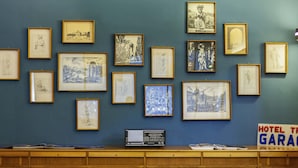 A wall with multiple framed sketches and a sign that reads 'HOTEL TRIGAR.'