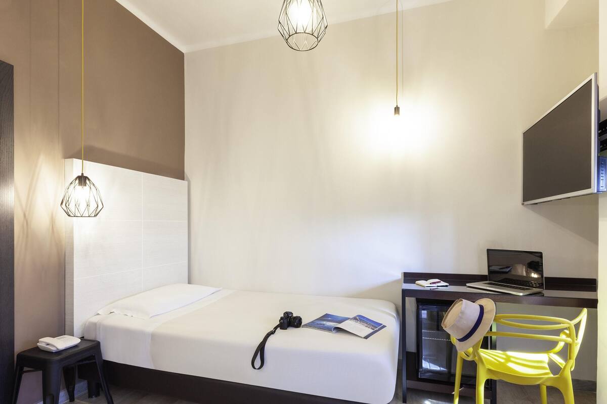 Una habitación de hotel moderna con cama, escritorio, silla y televisor.
