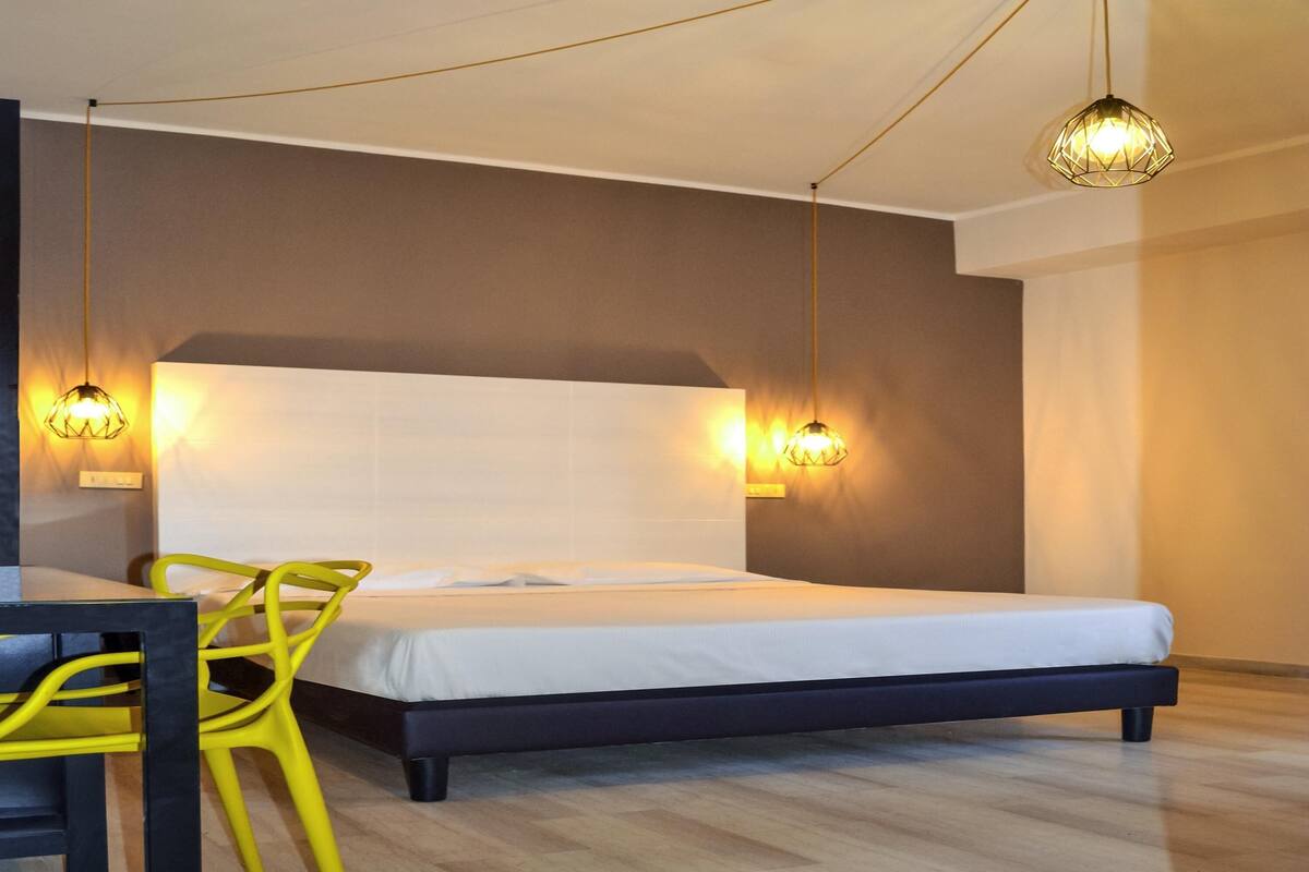 A modern hotel room with a bed, a desk, and a chair.