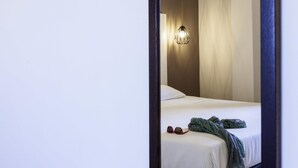 A bedroom with a bed, a hanging light fixture, and a pair of glasses on the bed. - ibis styles Trani (Trani)
