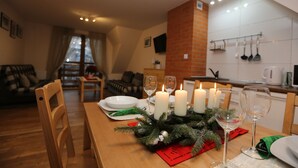 A dining area with a wooden table set for four, candles, and a Christmas decoration. - Maryna House - Widokowy Apartament (Zakopane)
