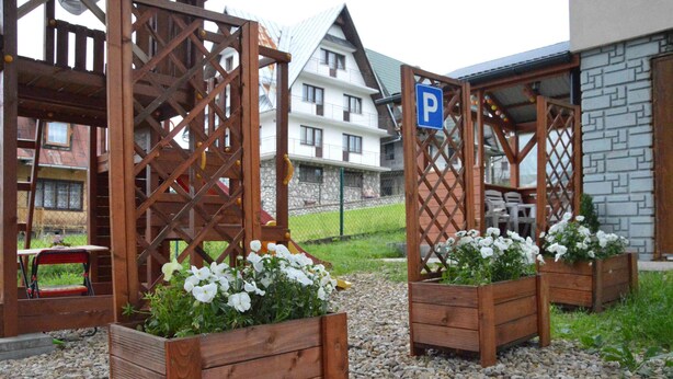 A wooden fence with flower planters, a parking sign, and a building in the background. - Maryna House - Widokowy Apartament (Zakopane)