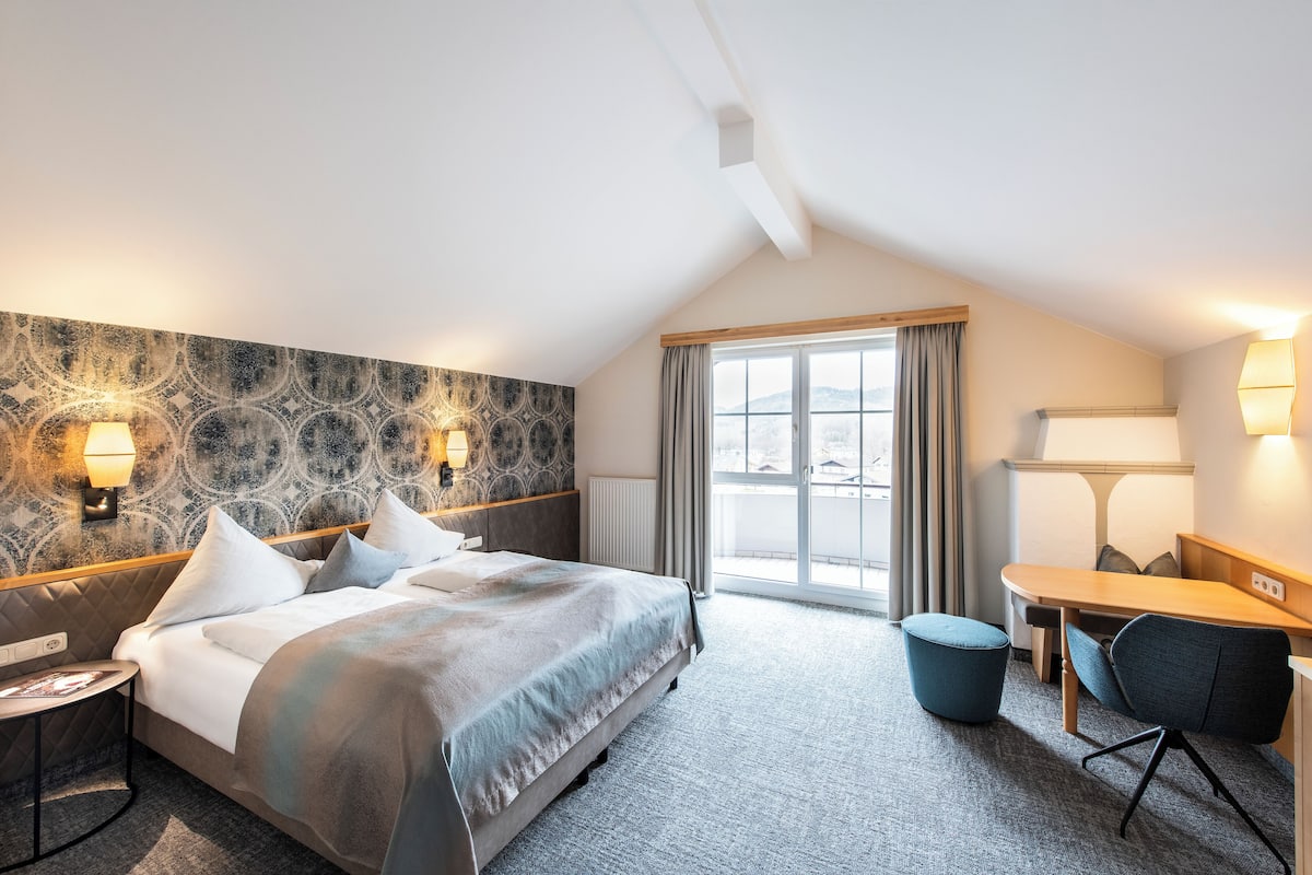 Habitación de hotel con cama, escritorio, silla y ventana con vista.