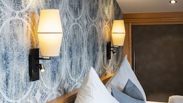 Une chambre d’hôtel avec un mur à motifs, deux lampes fixées au mur, un lit avec des oreillers et une tête de lit en bois.