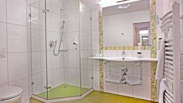 Un baño moderno con ducha envuelta en vidrio, lavamanos con tocador y un inodoro.