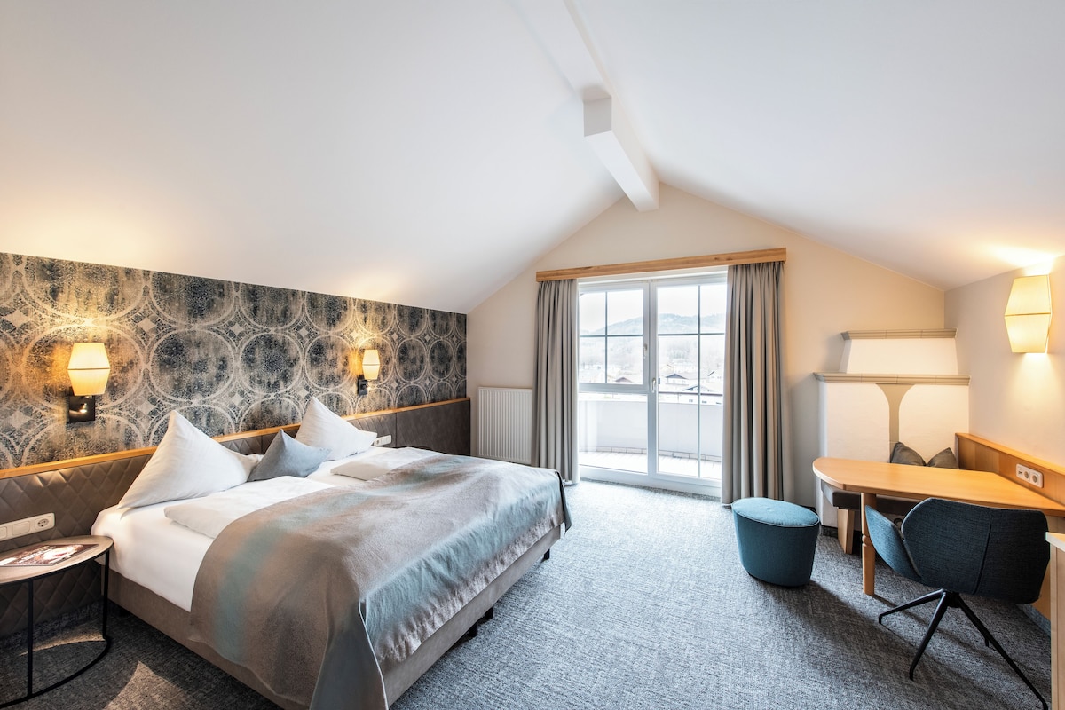 Hotellihuone, jossa on sänky, yöpöytä, lamppu ja näkymä ulos.
