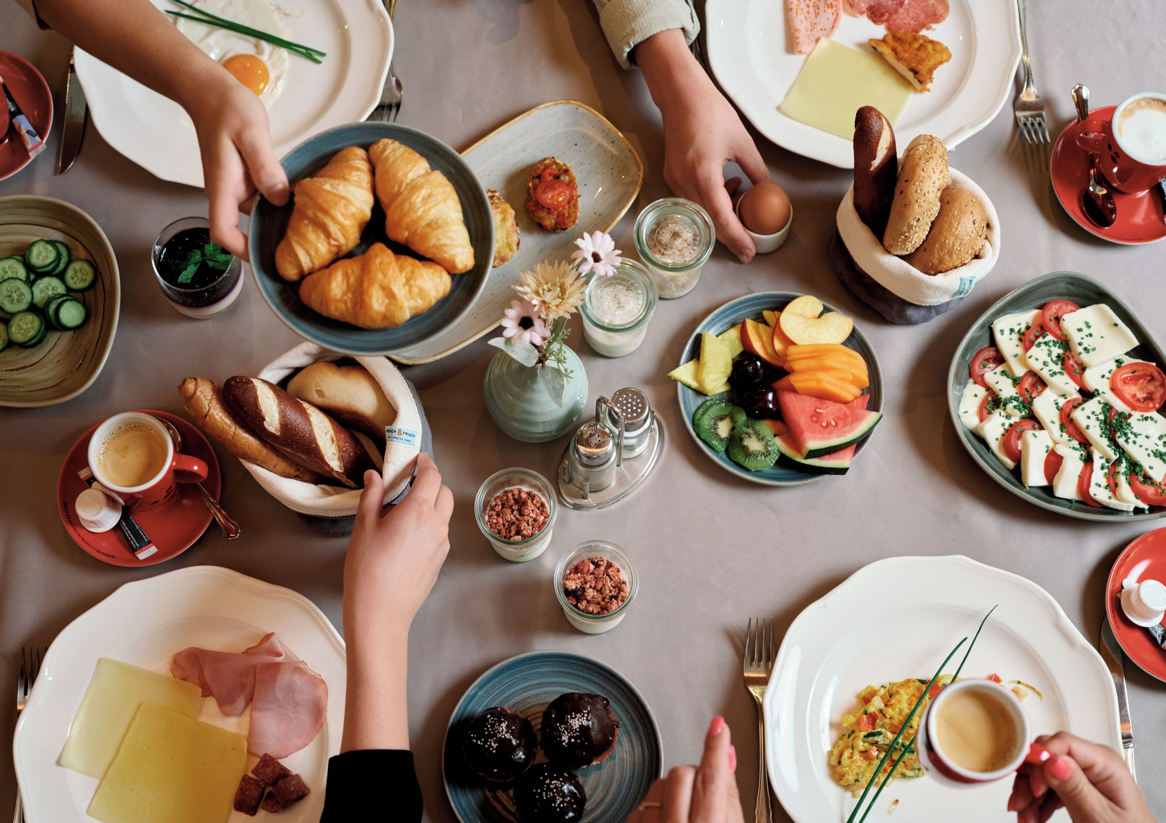 Une table dressée avec différents plats, notamment du pain, des fruits et du fromage, ce qui laisse supposer qu’un repas va être servi.