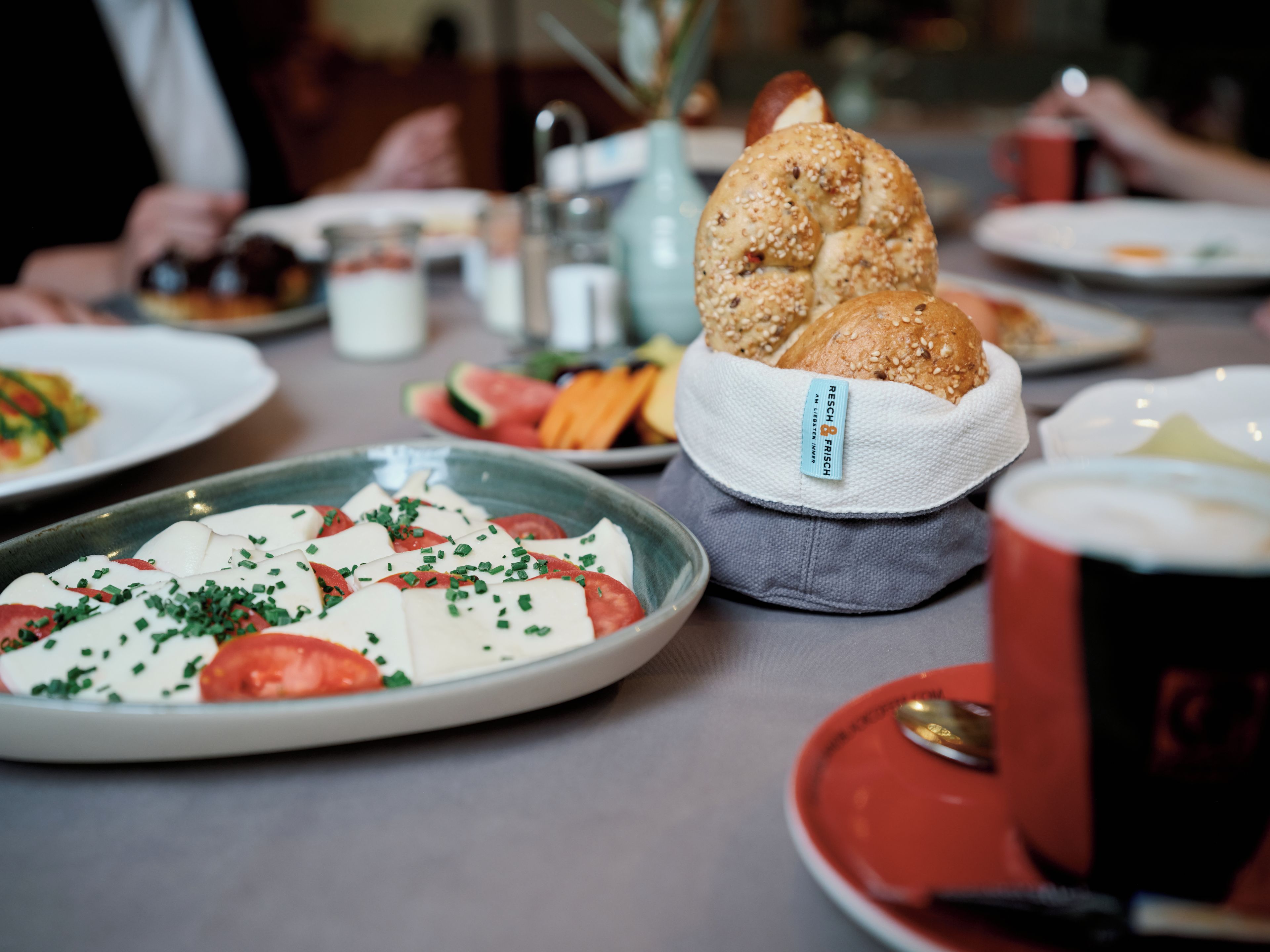 Una mesa de comedor con un plato de comida, una cesta de pan y una taza de café.