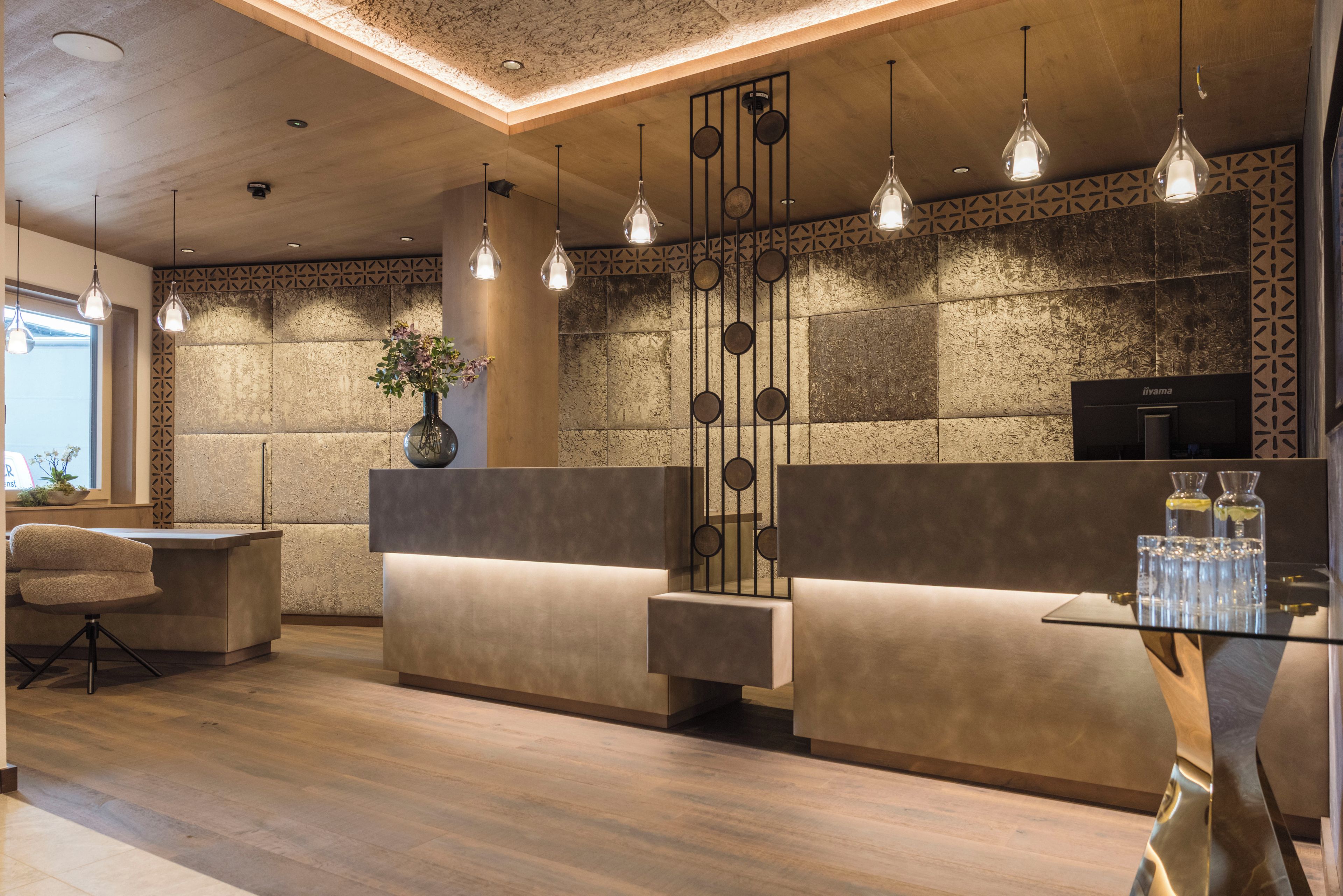 A modern reception area with a wooden reception desk, a sofa, and a glass table with water bottles.