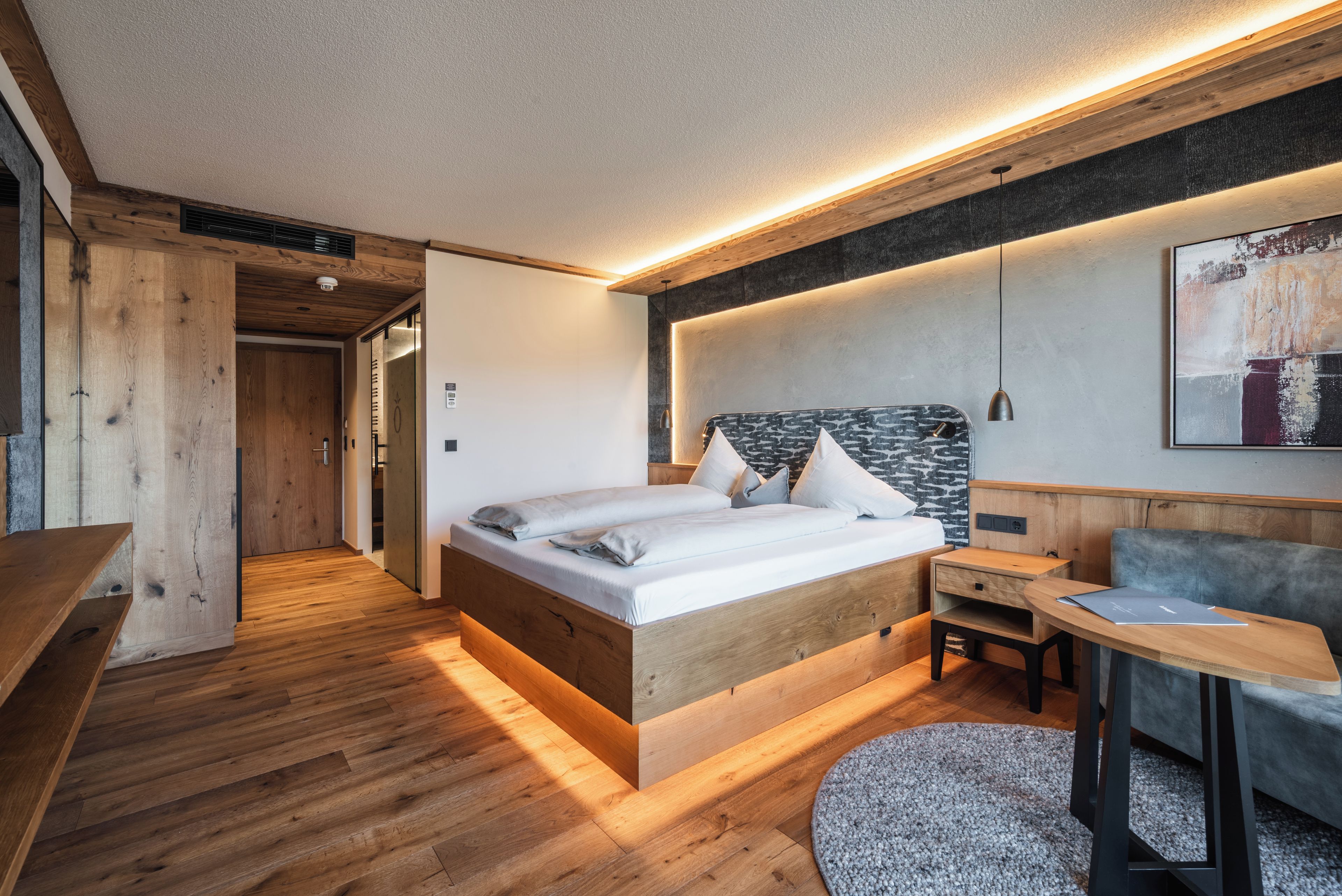A modern bedroom with a wooden bed, bedside table, and a small desk with a chair.