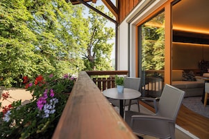 Una terraza de madera con una mesa y sillas, con vista a un jardín lleno de plantas y flores.