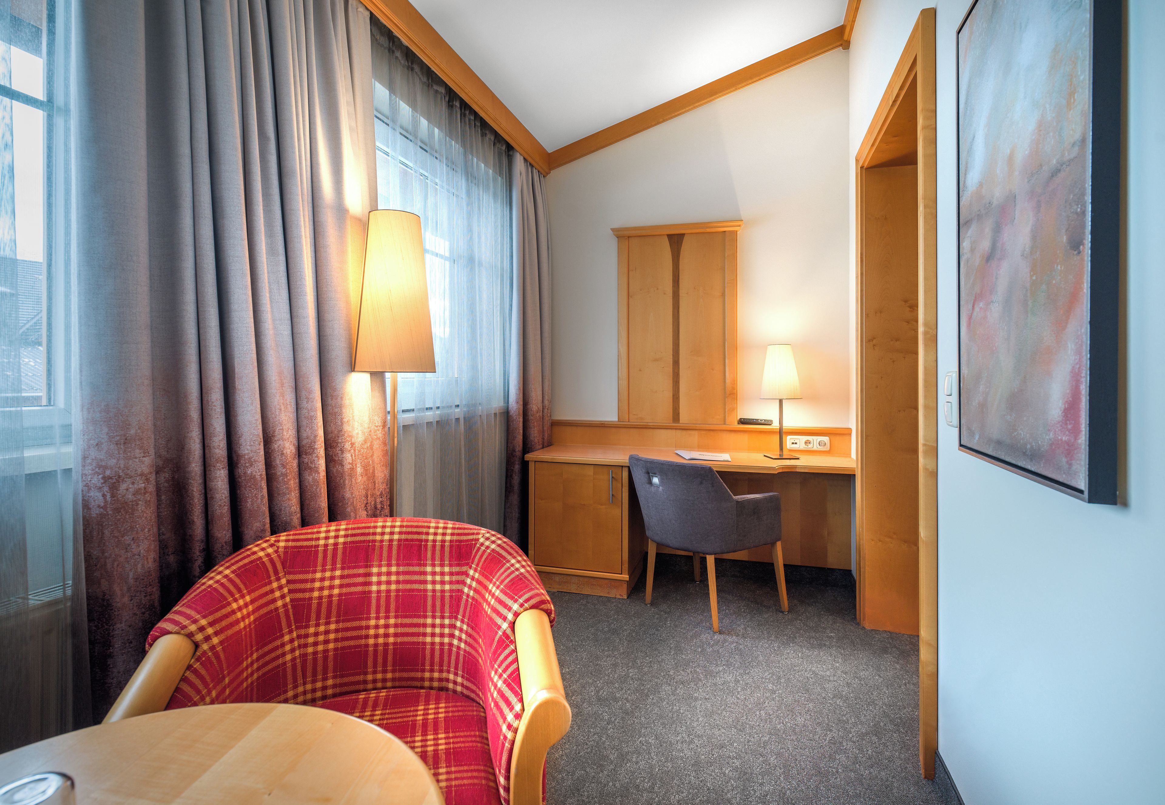 Una habitación de hotel con una cama, un escritorio, una silla y una lámpara.
