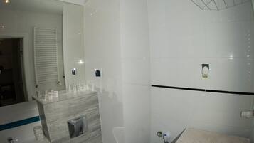 A modern bathroom with a white sink, toilet, and washing machine, a mirror, and a towel rack.