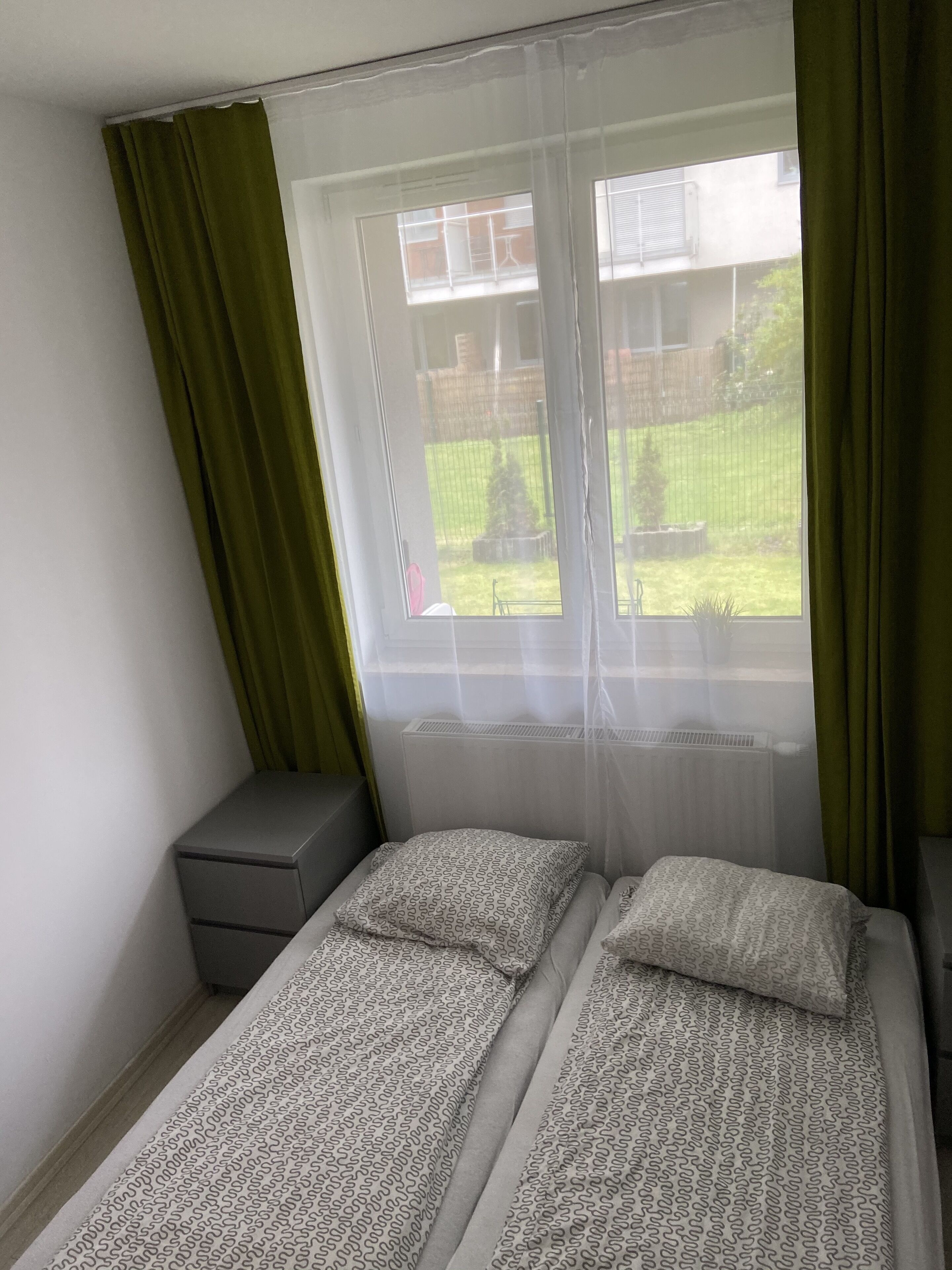 Una habitación pequeña con cama individual y ventana que da a un jardín.