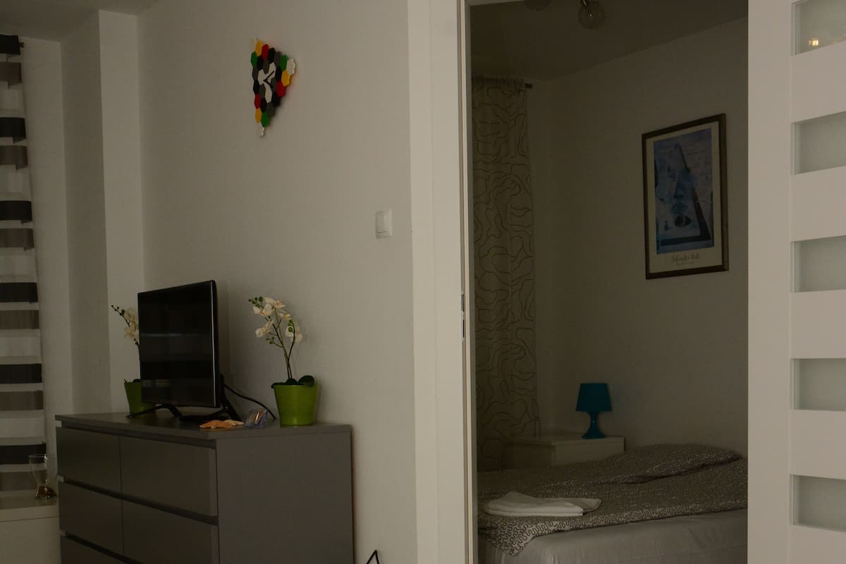 Une chambre à coucher avec un lit, une commode, un téléviseur et une petite table avec une lampe.