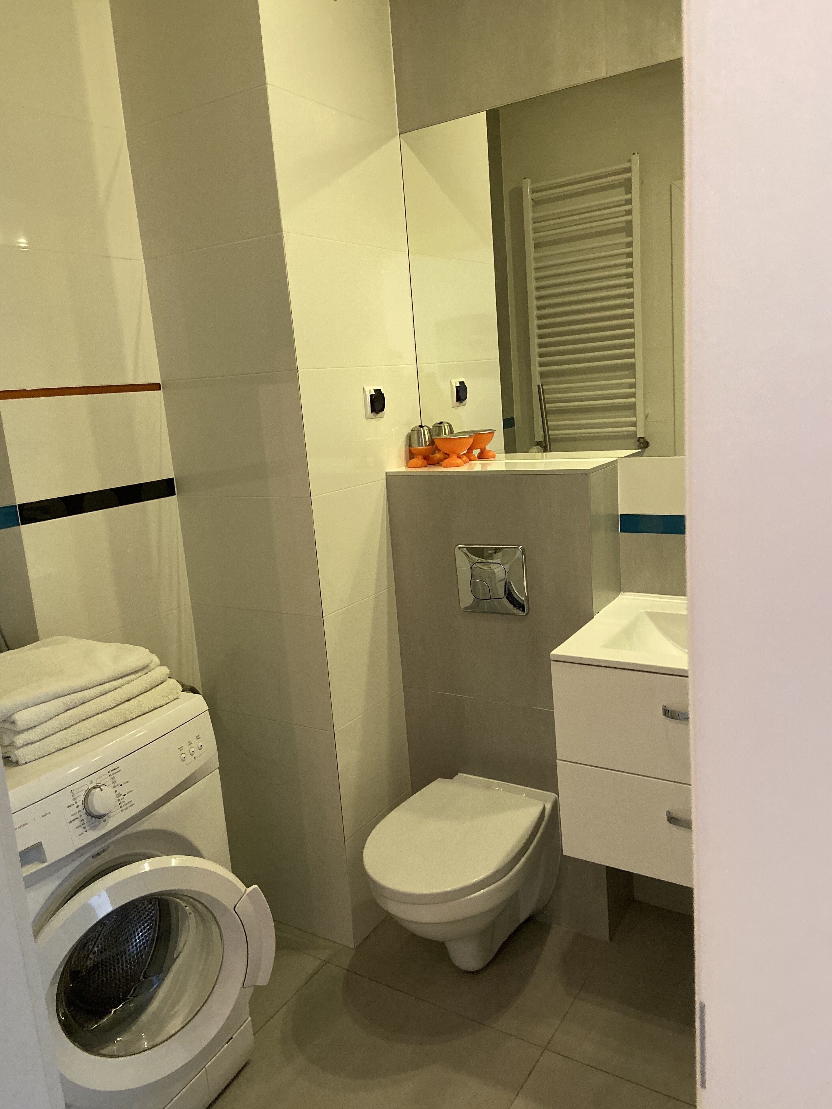 Une petite salle de bain équipée d’un lave-linge, de toilettes et d’un lavabo.