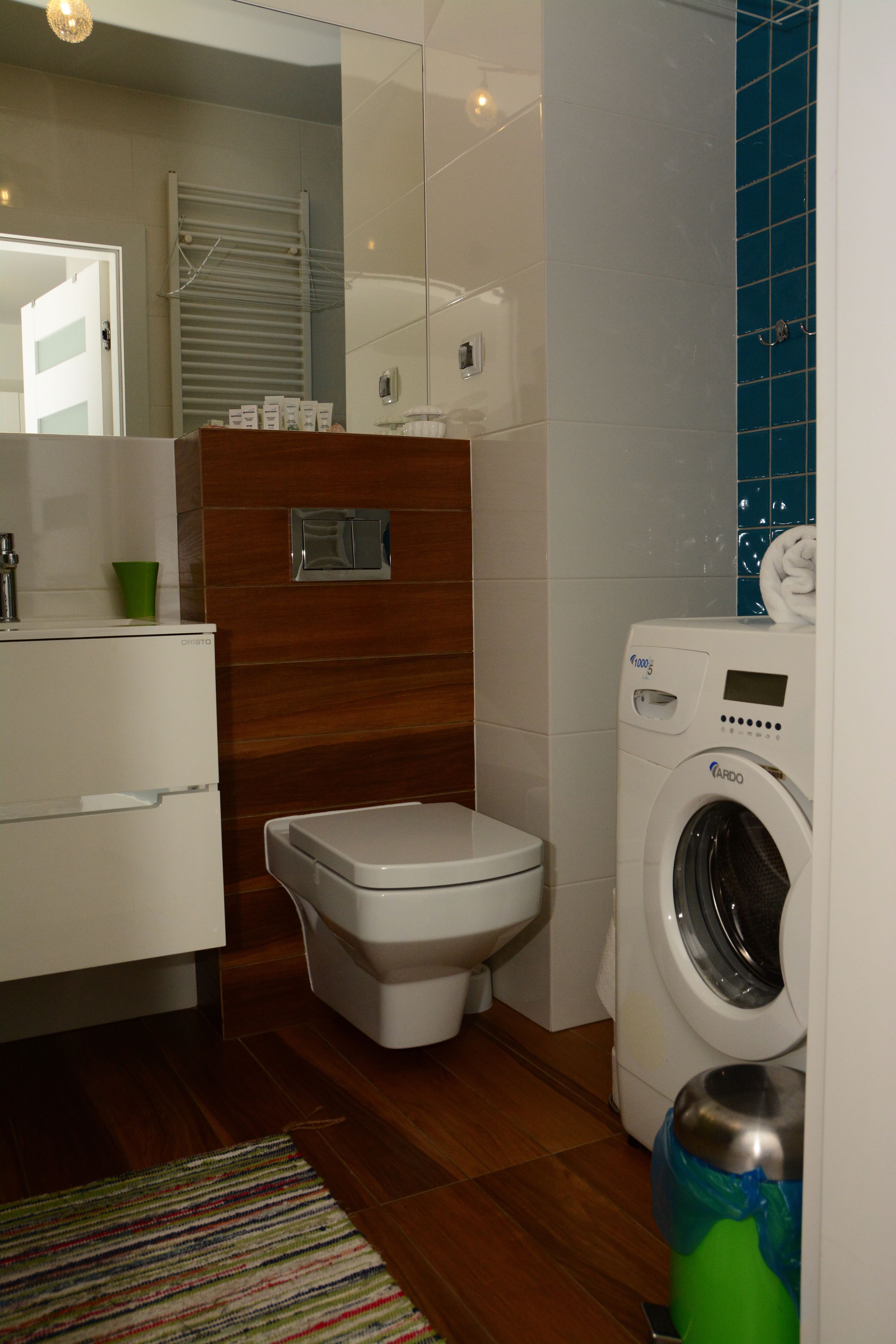 A compact bathroom with a toilet, washing machine, and a small cabinet.